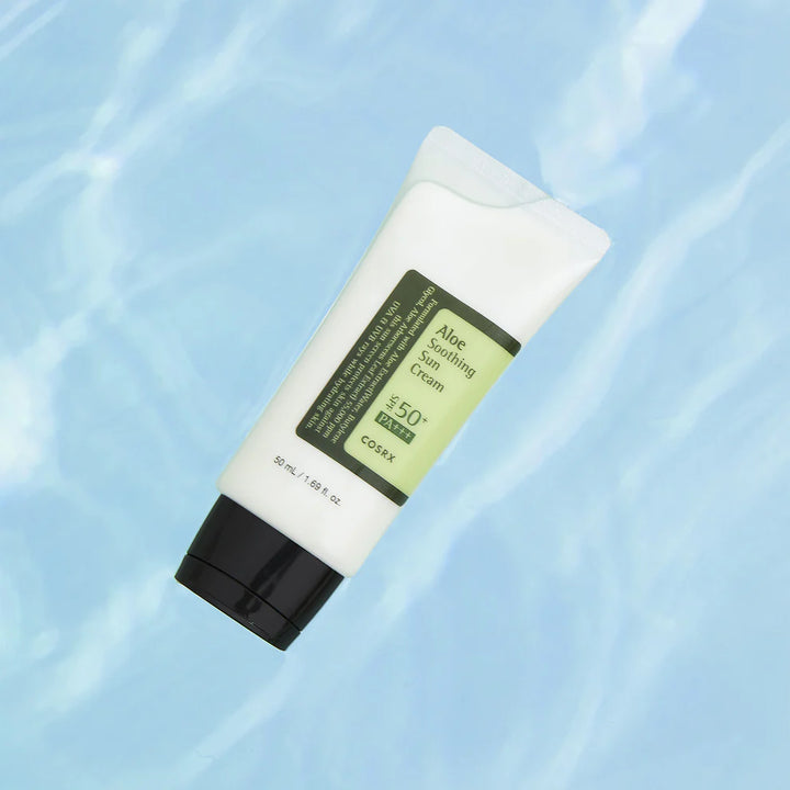 COSRX Aloe Soothing Sun Cream tube lying on a water-textured blue background.