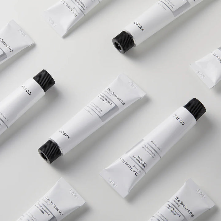 Flat lay of COSRX Retinol 0.3 Cream tube with skincare routine essentials