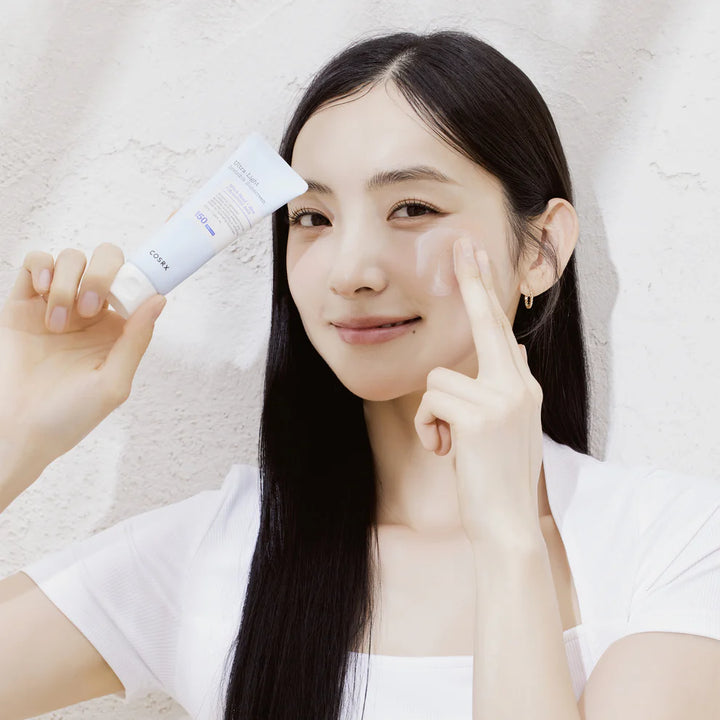 “Model applying COSRX Ultra-Light Invisible Sunscreen – non-greasy Korean SPF50 for glowing skin”